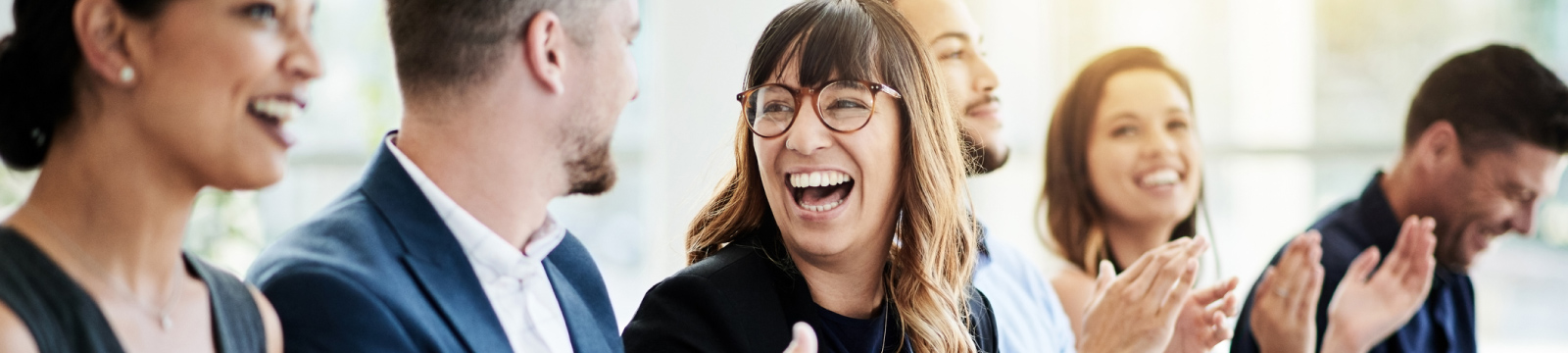 A happy woman clapping looking at a coworker